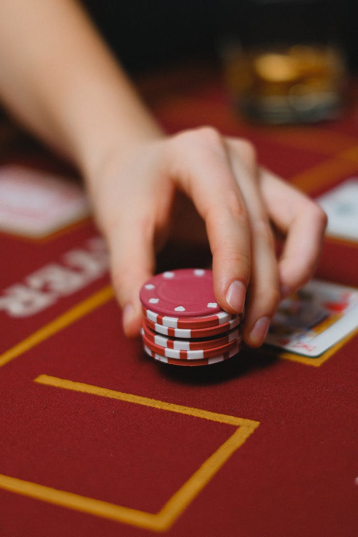 services-02 A detailed close-up of a hand holding red poker chips on a casino table.